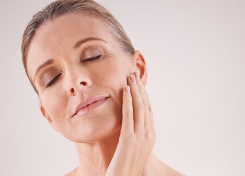 Photo of a middle-age woman with great skin touching her face and closing her eyes